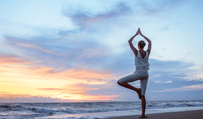 Woman doing yoga pose looking over ocean